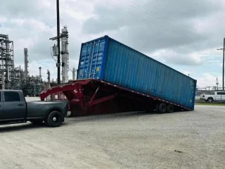 A tilt bed trailer lowering a shipping container